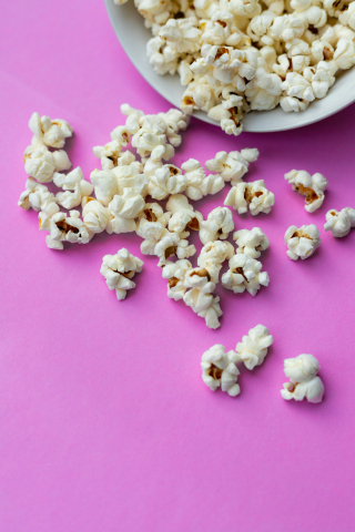 Popcorn ligger utspritt på ett rosa bord.