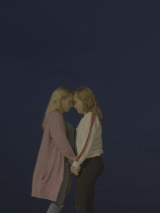 Två unga kvinnor håller om varandra mot en natthimmel
