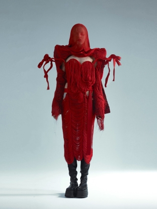 En kvinna helt klädd i en kreation i röda tyger och trådar. 