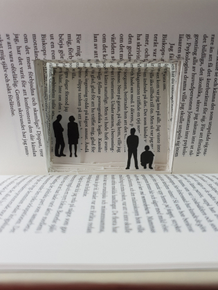 Inuti en bok är ett litet rum skapat där några små figurer befinner sig.