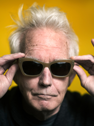 En man i solglasögon framför gul bakgrund