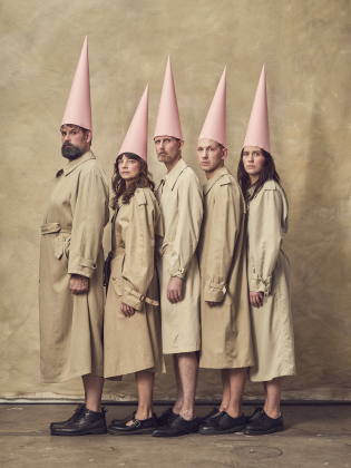 Fem vuxna i beiga trenchcoats och rosa konhattar står i profil tätt intill varandra mot beige bakgrund.