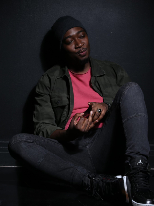 En man i rosa tröja mot en mörk vägg