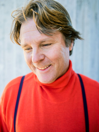 En leende man i röd polo