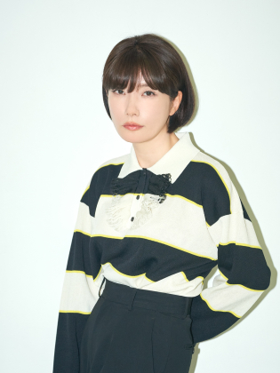 Mieko Kawakami står mot en ljus bakgrund i ett minimalistiskt porträtt med tydliga kontraster och ett lugnt, fokuserat uttryck.
