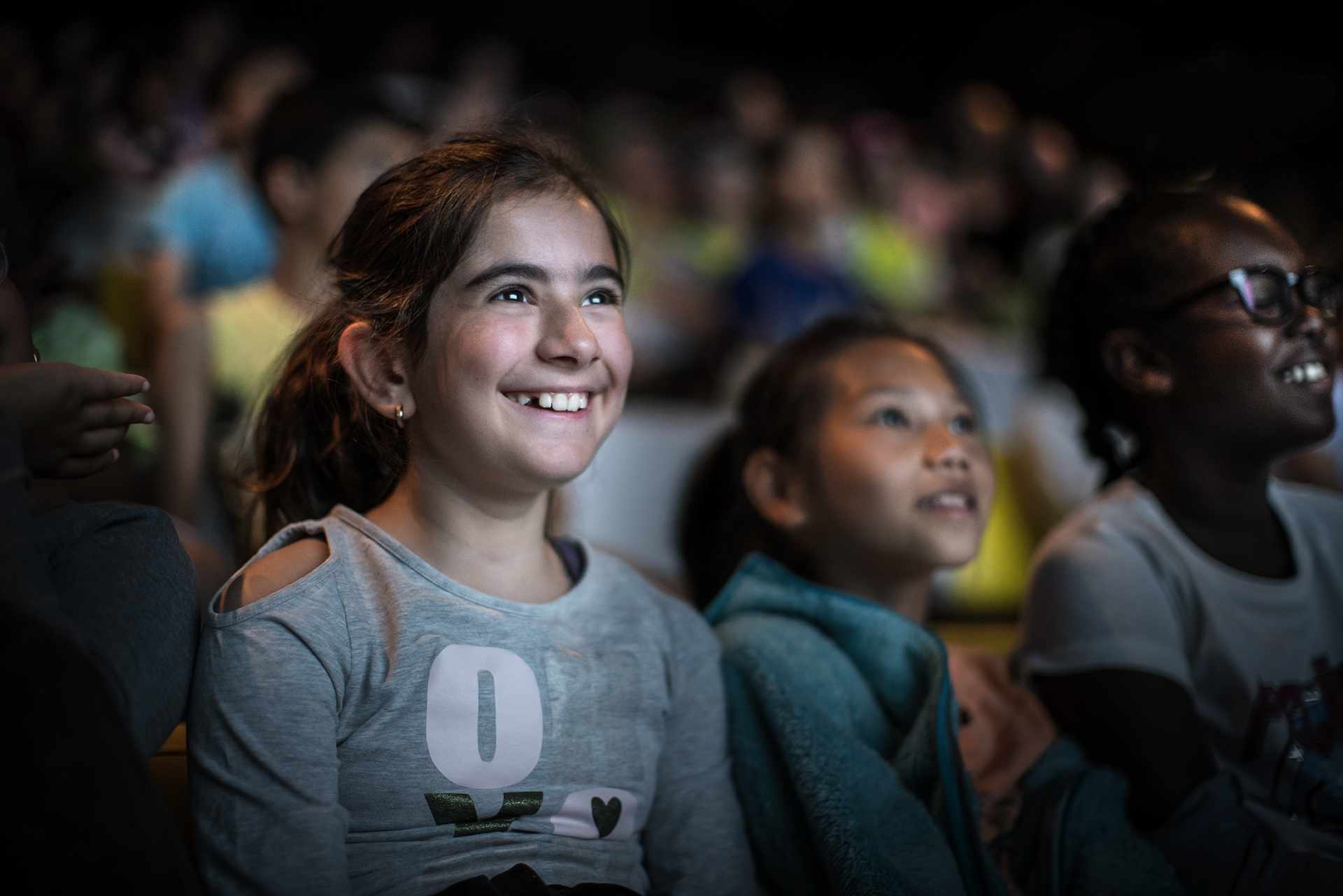 Tre barn som tittar på en film eller föreställning