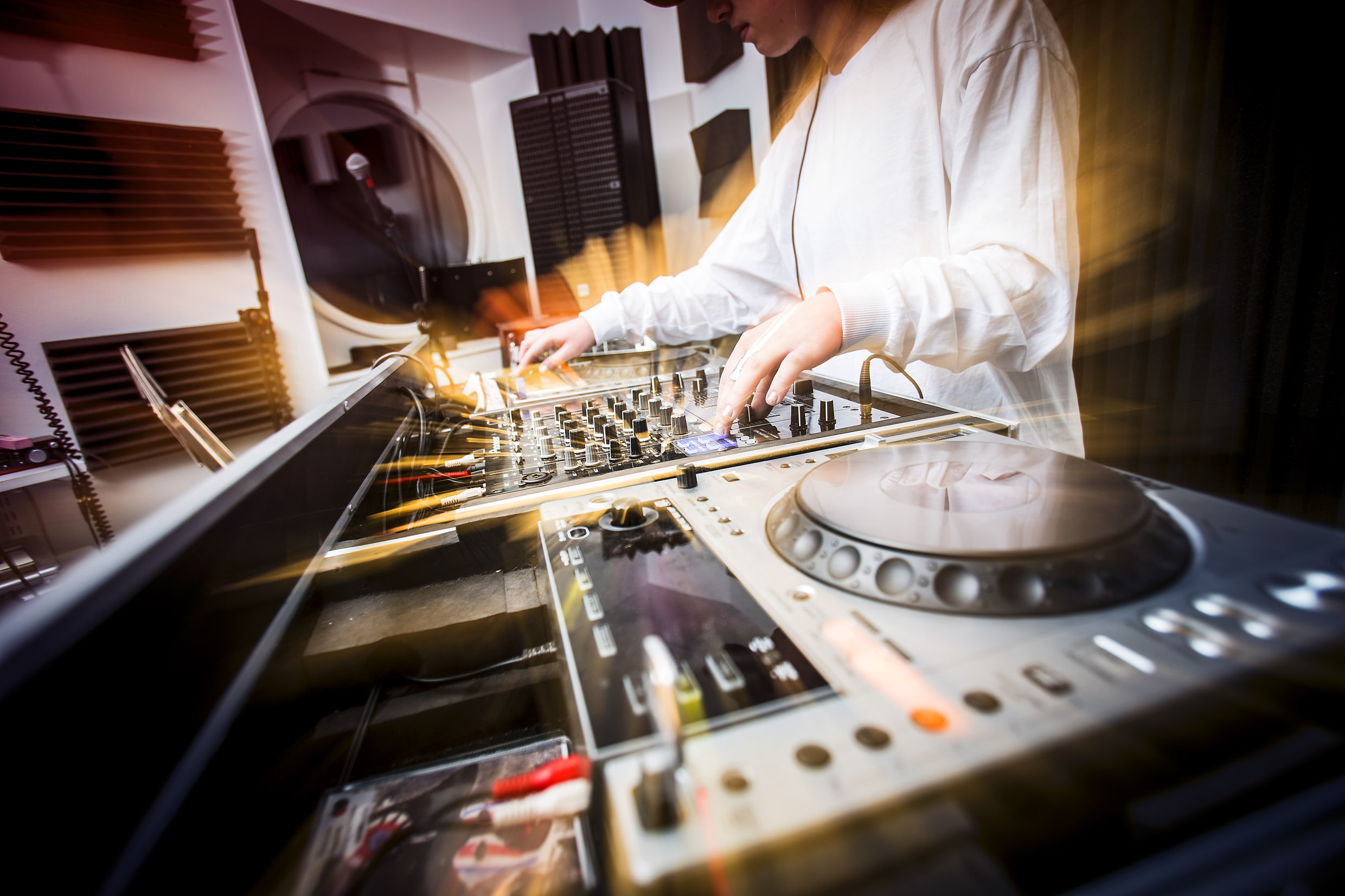 En person står vid ett DJ-set och spelar musik. 