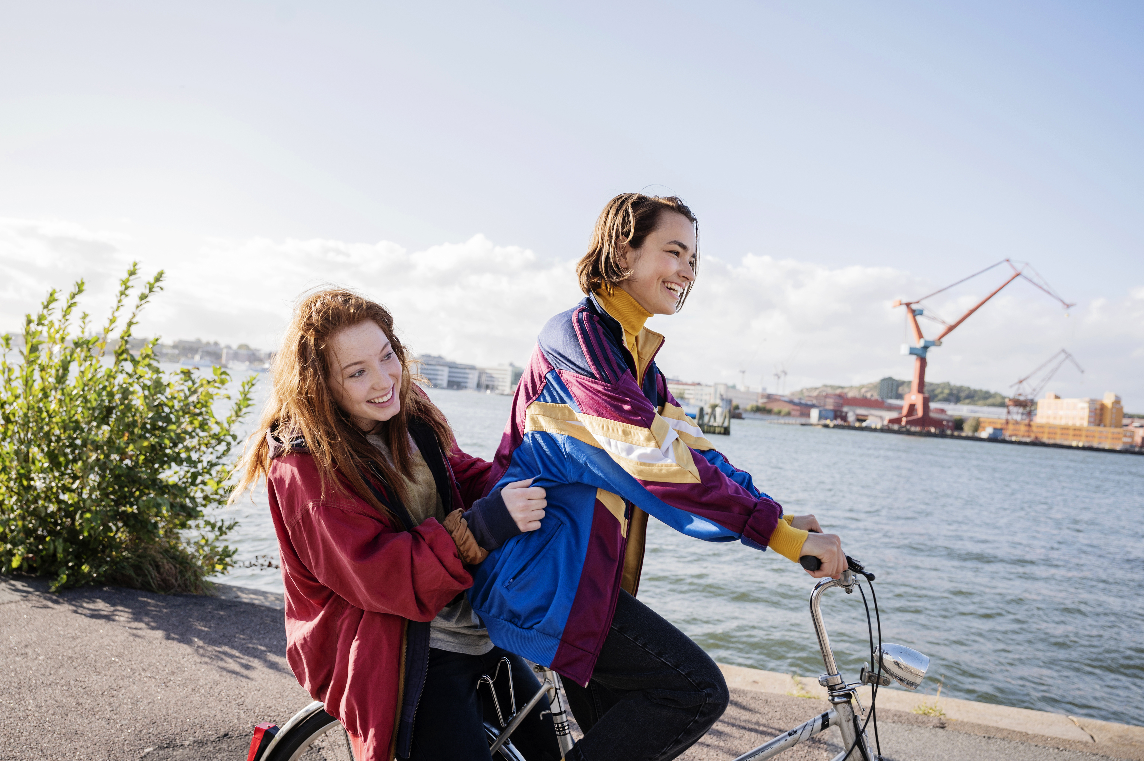Två flickor åker på en cykel och skrattar