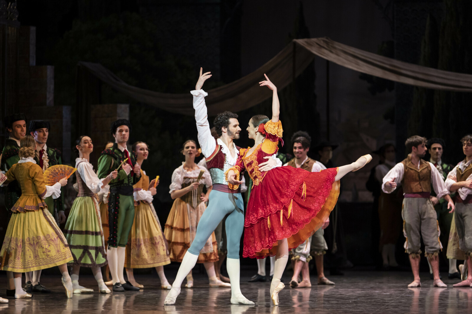 En balettensemble i spanska kostymer dansar på en scen