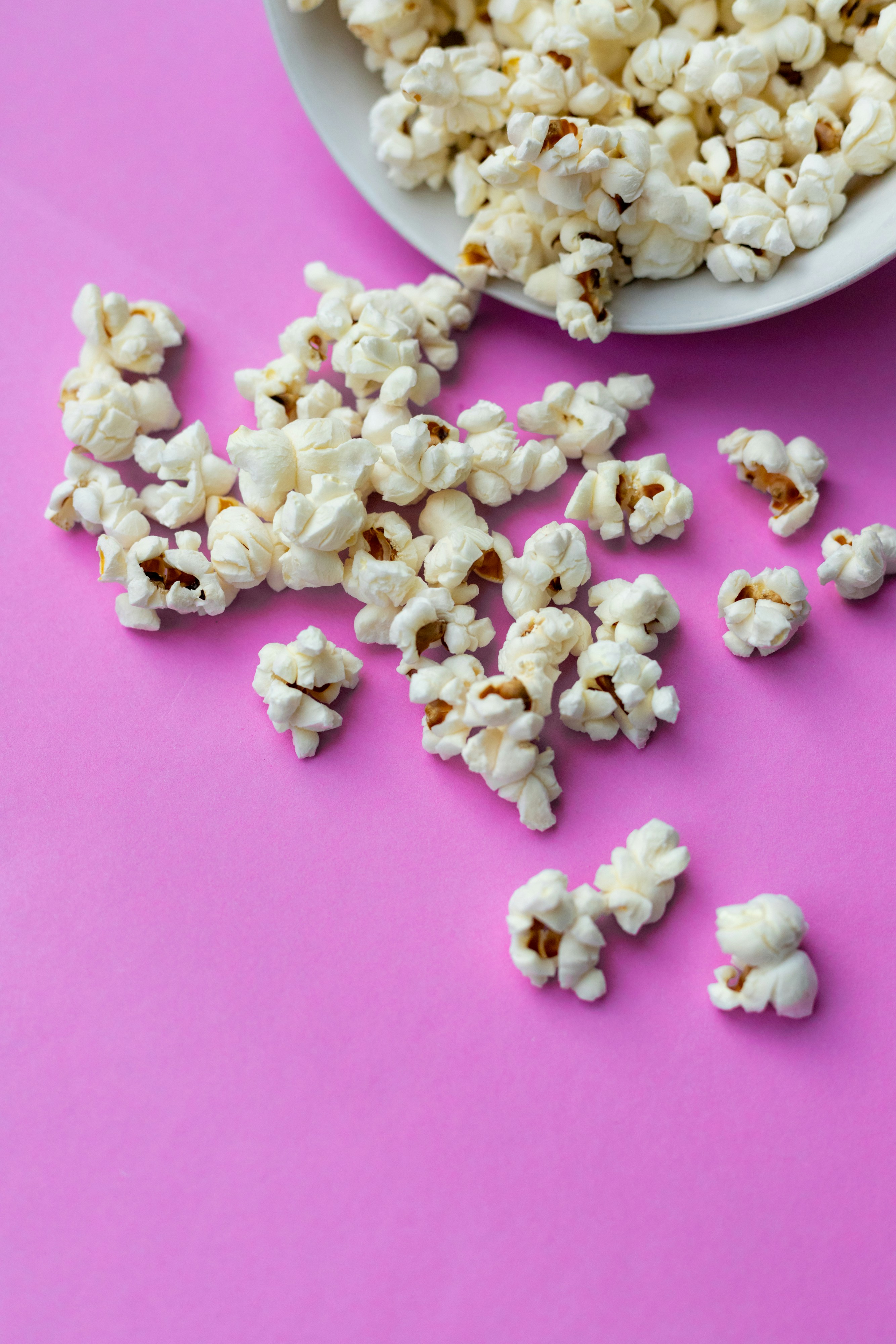 Popcorn ligger utspritt på ett rosa bord.