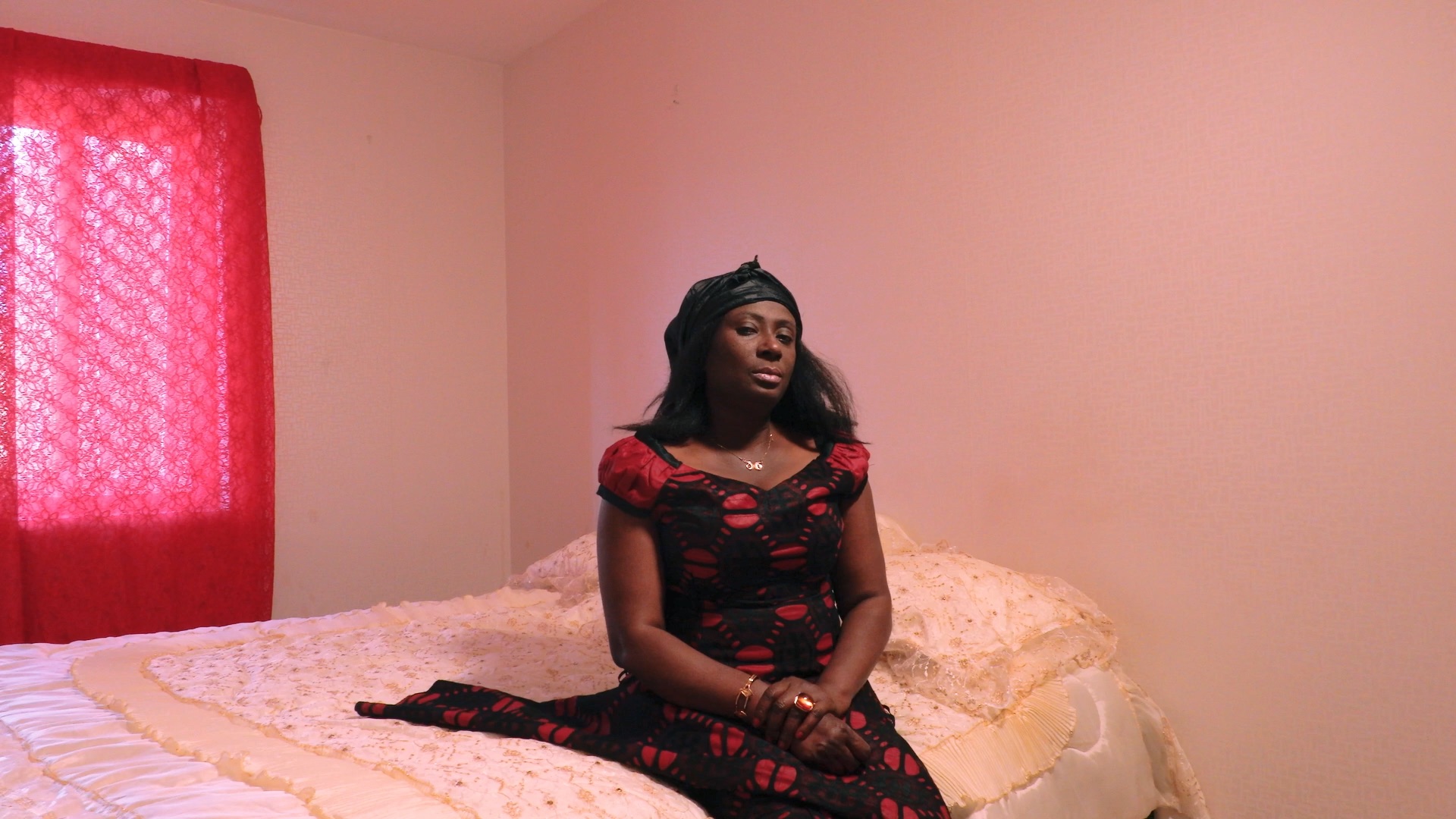 En kvinna sitter på en säng i ett rosa rum.