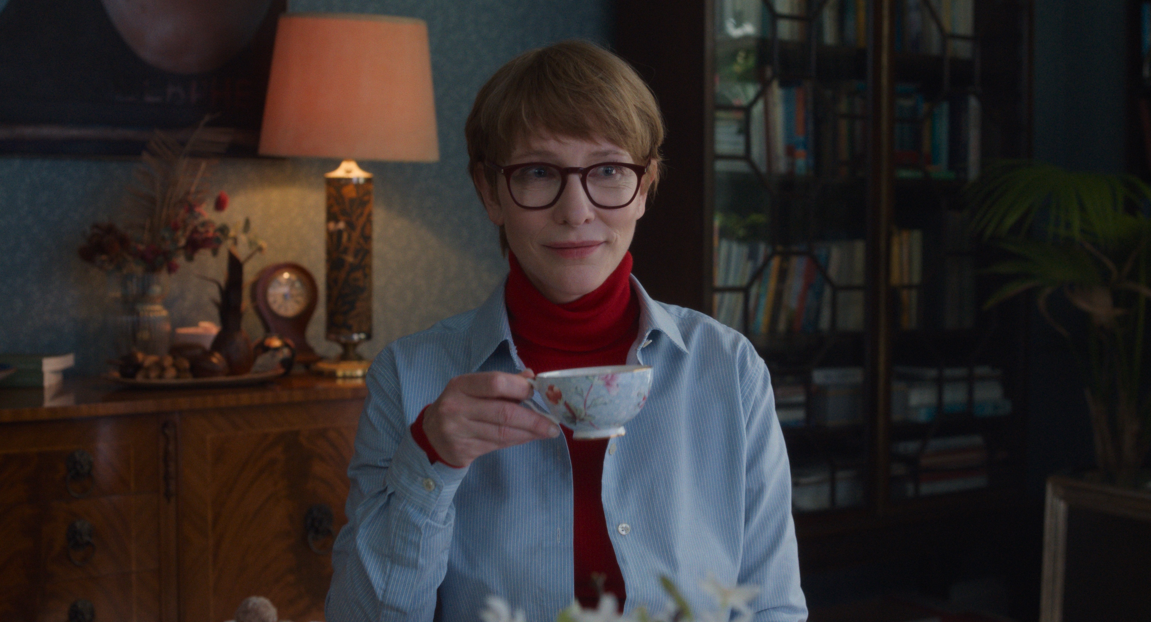 En kvinna håller en tekopp och ler.