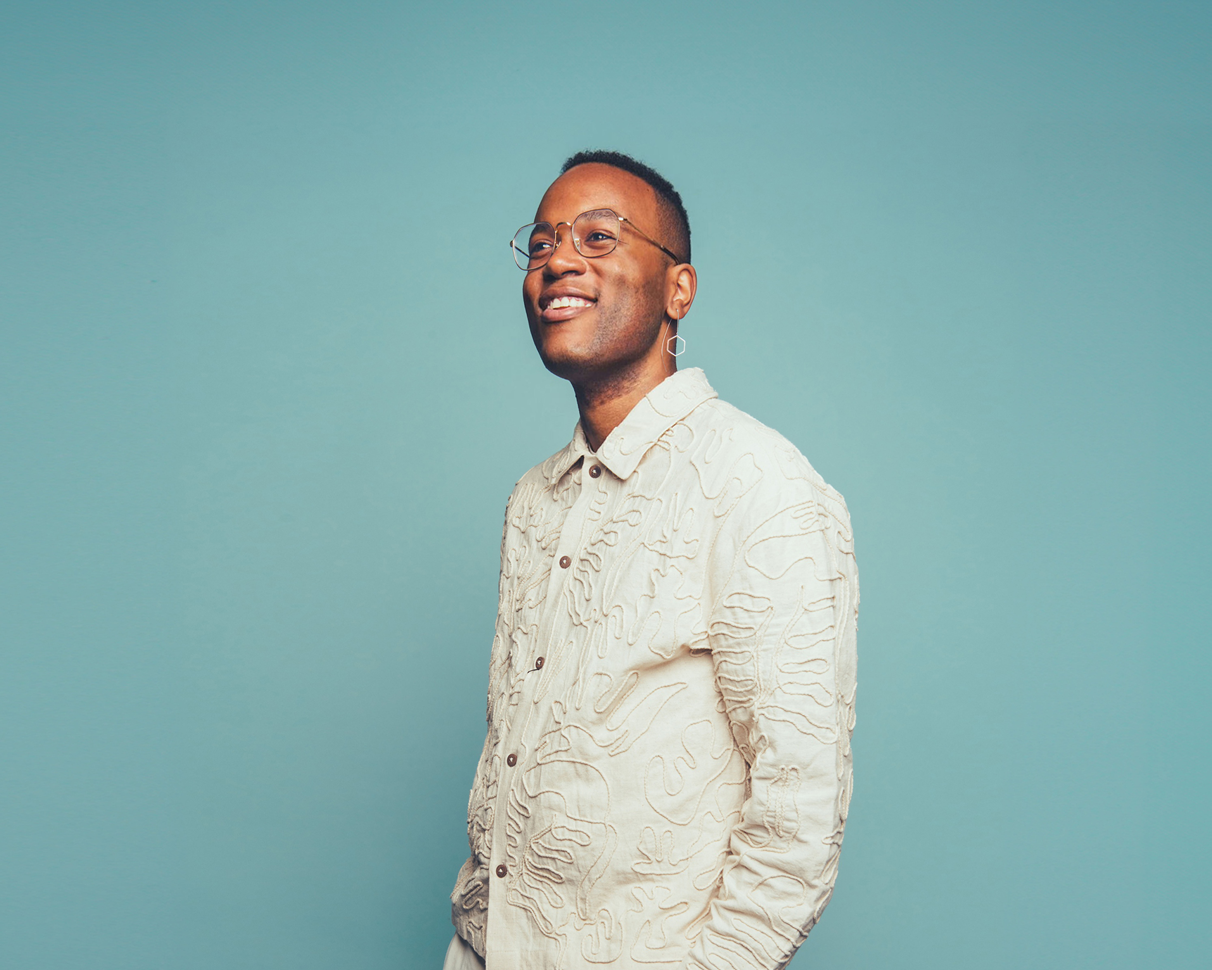 En man i vitt framför turkos bakgrund