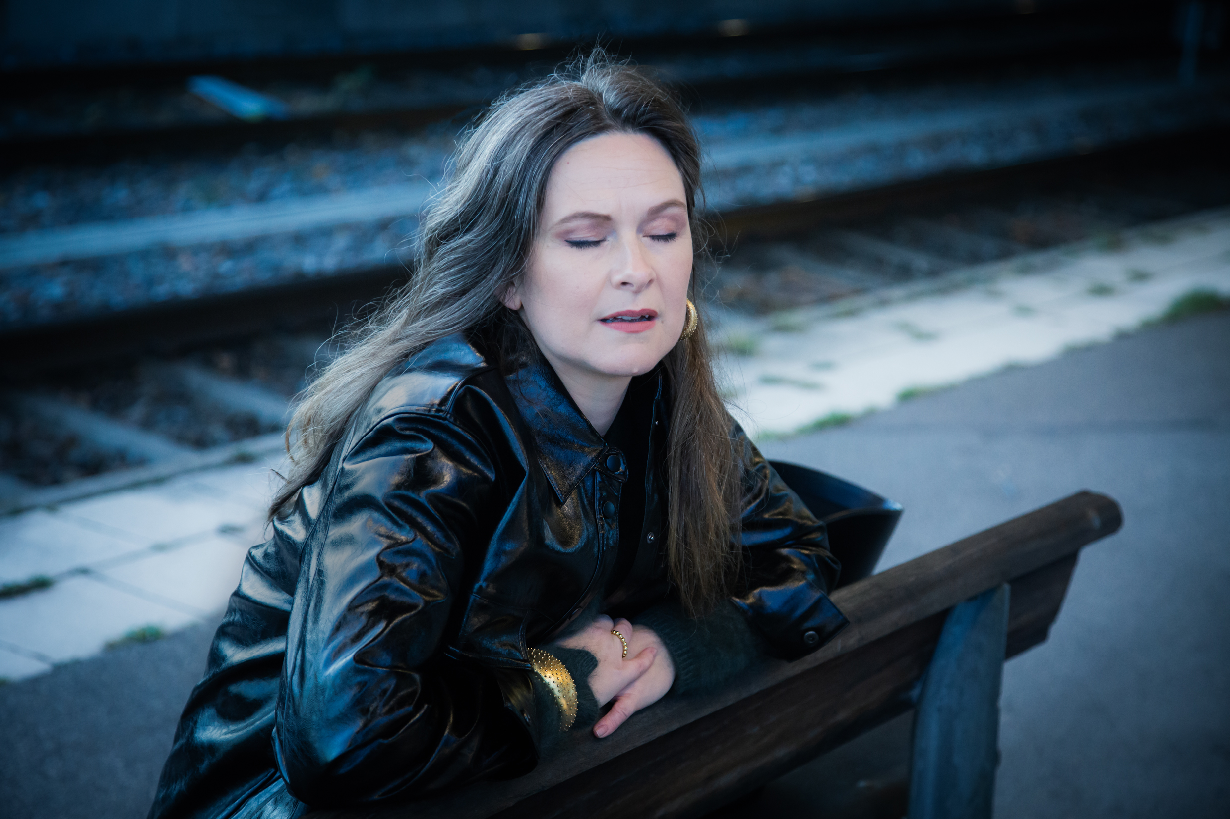 En kvinna sitter på en bänk och blundar.
