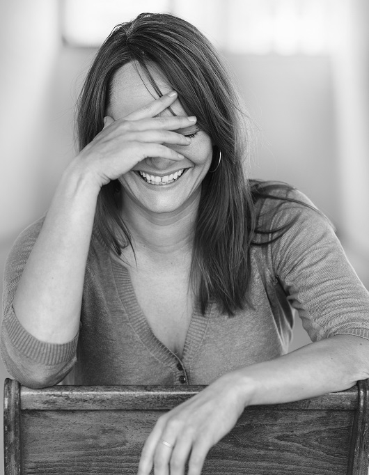 Porträtt på serieskaparen Maren Uthaug, hon skrattar och håller en hand mot pannan. 