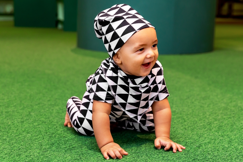 Ett litet barn med kläder i svartvitt triangelmönster från topp till tå. 