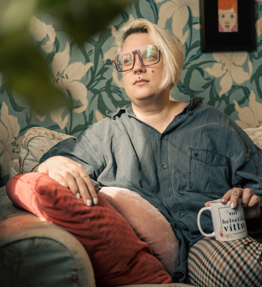 Serieskaparen Emmi Valve sitter i en soffa med en kopp i handen. 