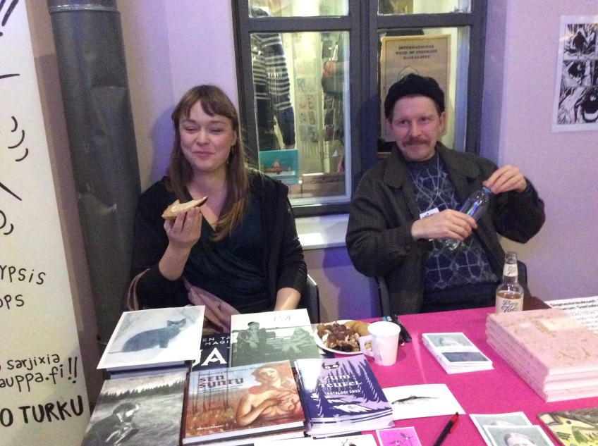 Två personer sitter vid ett bord med seriealbum på. 