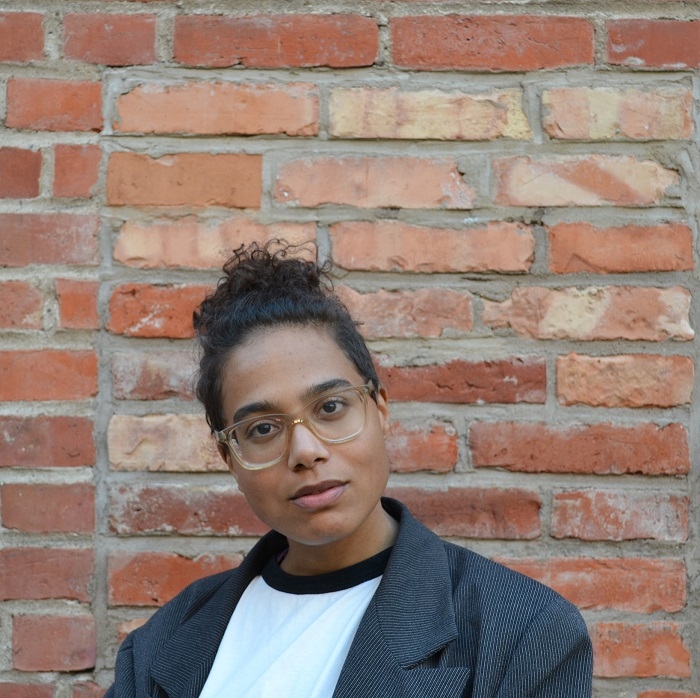 Konstnären Ina Nian framför en tegelvägg. 