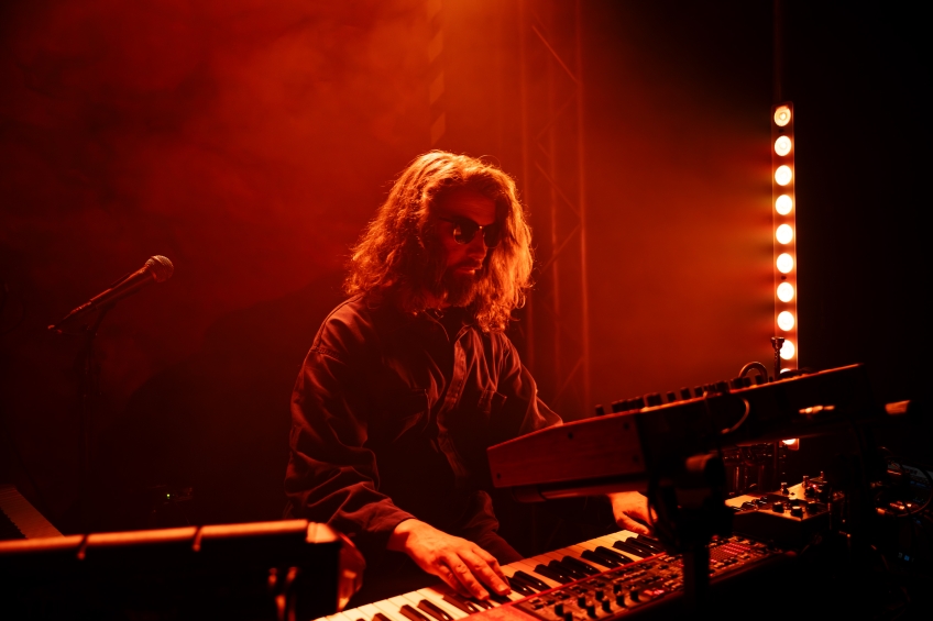 Mats Björke spelar keyboard i ett rött ljus. Han har solglasögon på sig