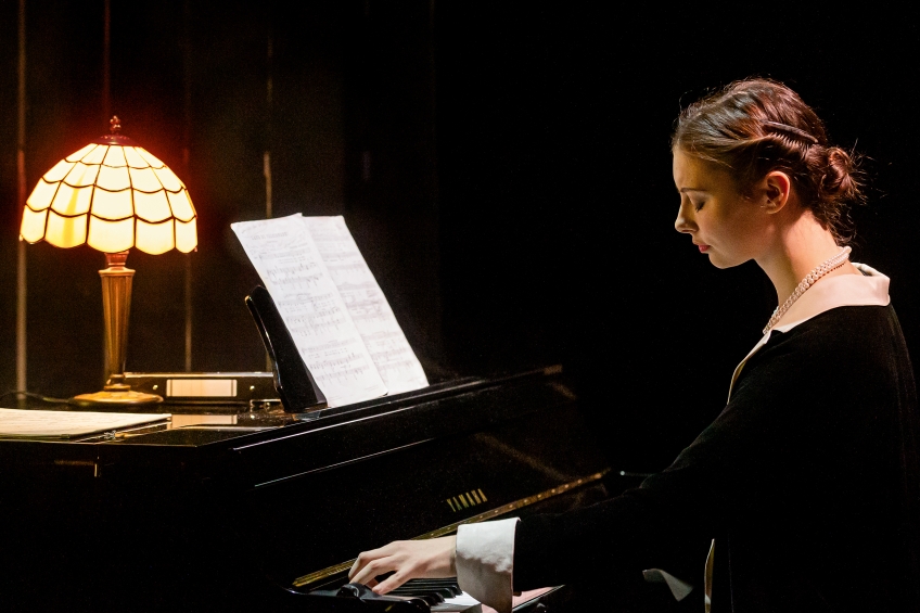Astri Aareskjold vid pianot med en lysande lampa på pianot