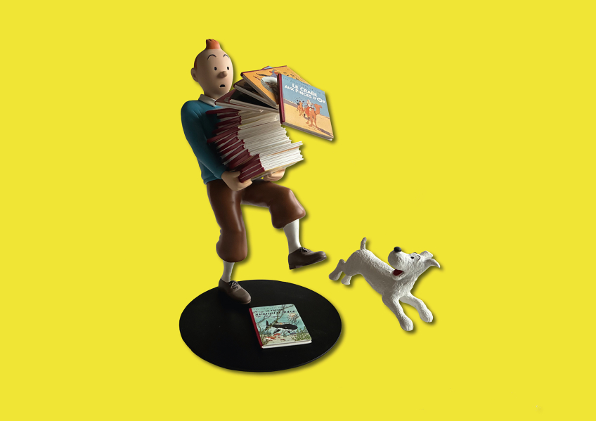 Figur av Tintin som tappar en hög seriealbum, med hunden Milou hoppande bredvid på gul bakgrund.