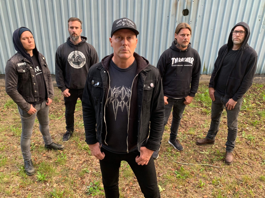 Fem svartklädda män framför ett hus