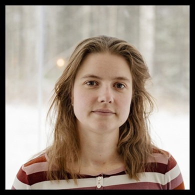 En ung person med neutralt uttryck, fotograferad utomhus i ett vinterlandskap med suddiga träd i bakgrunden.