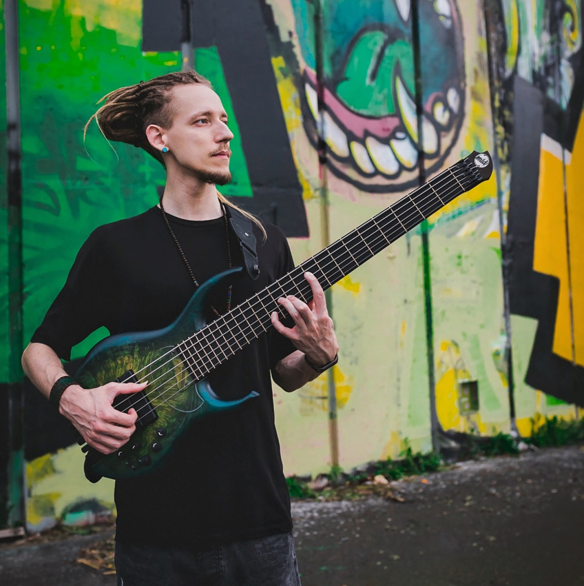 Musikern Zlatoyar spelar elbas framför en vägg med färgstark graffiti.