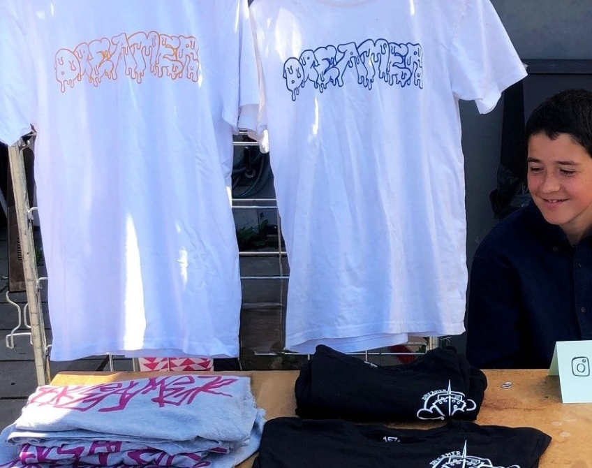 T-shirts och andra trycksaker visas upp på ett bord under en marknad.