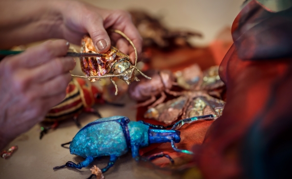 En person tillverkar insekter som ska användas på Marionetteatern. 