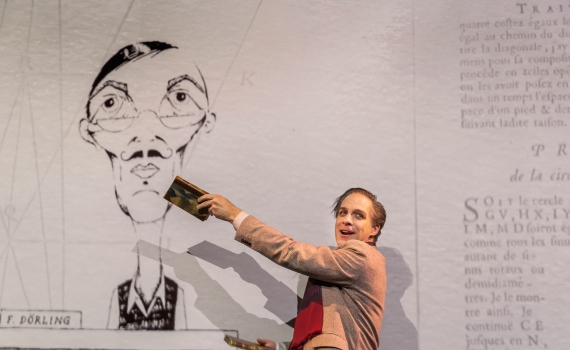 Fredrik Meyer med en bok handen framför en teckning föreställande en bokförsäljare