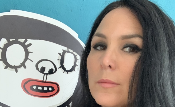 Nina Hemmingsson framför en bild av en figur hon illustrerat. 