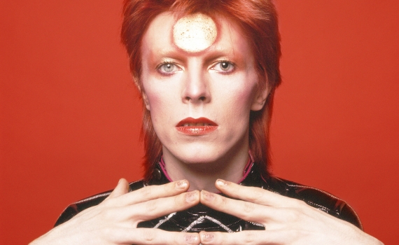 Artisten David Bowie med rött hår mot en röd bakgrund. 