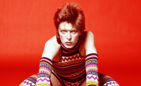 Artisten David Bowie i färgglada kläder och rött hår. 