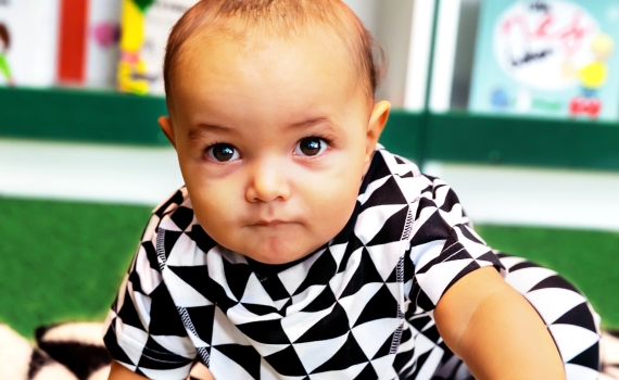Ett litet barn med kläder och filt i svartvitt triangelmönster. 