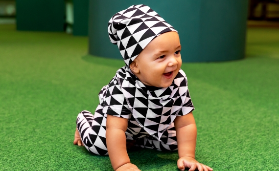 Ett litet barn med kläder i svartvitt triangelmönster från topp till tå. 