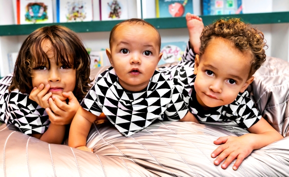 Tre barn med kläder i svartvitt triangelmönster. 