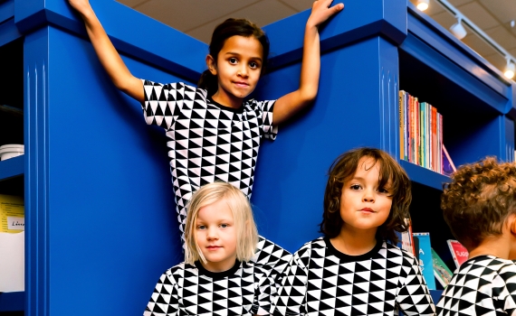 Fem barn med kläder i svartvitt triangelmönster. 