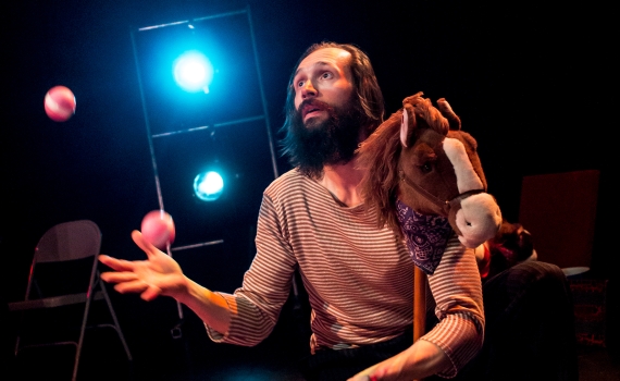 Cirkusartist som jonglerar bollar på scenen. 