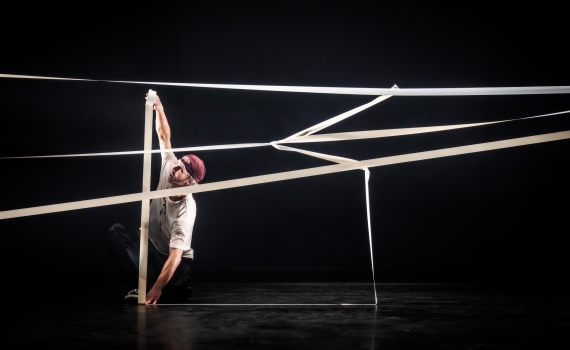 Dansaren Fredrik Benke Rydman skapar en konstruktion med hjälp av vit tejp. 