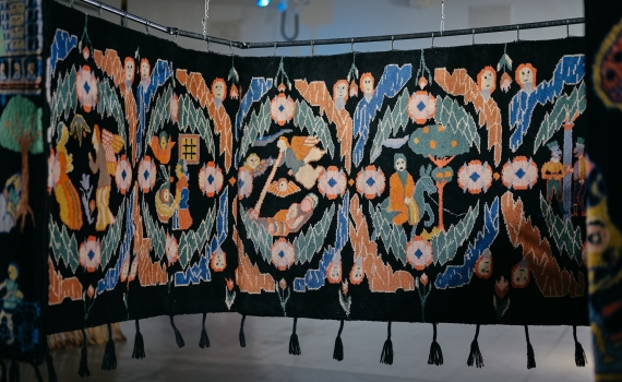 En stor matta med olika mönster och motiv på hänger på en ställning. 