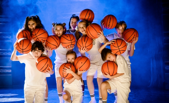 Flera barn håller i basketbollar i musikalen Matilda The Musical. 