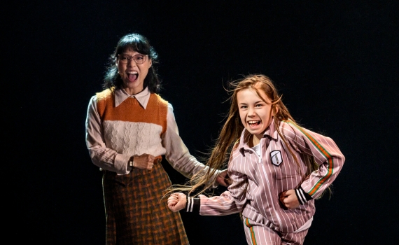 En vuxen och ett barn dansar på scen i musikalen Matilda The Musical. 