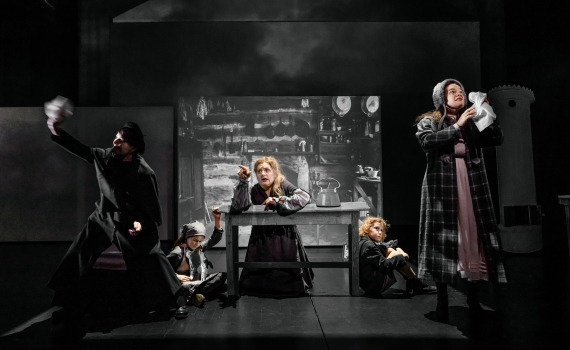Fem skådespelare, både barn och vuxna, på scenen i pjäsen Skuggan över stenbänken. 