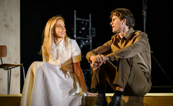 En man och en kvinna sitter ner på scenen i föreställningen Tre systrar. 