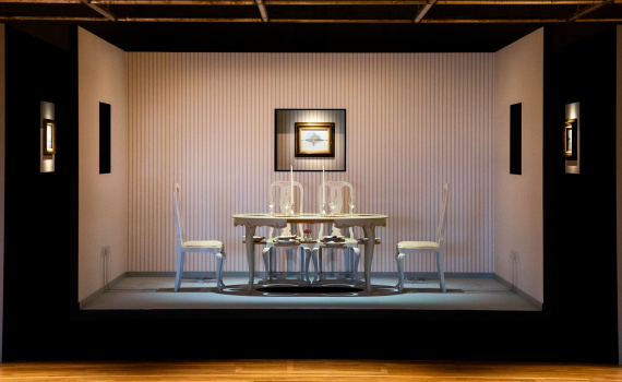 Upplyst matbord med sex stolar, dukning och två ljus, placerat i ett rum med randig tapet.