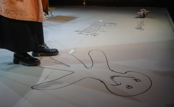 En kvinna som står på en målad streckgubbe som är ritad på golvet