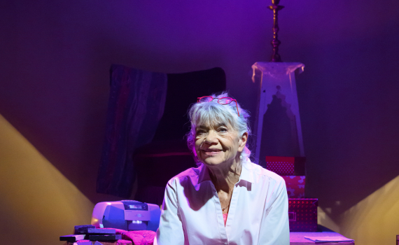 Iwa Boman sitter i ett lila ljussatt rum.