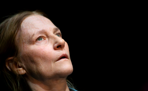 Närbild underifrån av medelålders kvinna med ljust hår och blå skjorta som tittar uppåt.